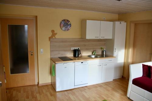 a kitchen with white cabinets and a clock on the wall at Ferienwohnung Sonja am Weinberg in Radebeul