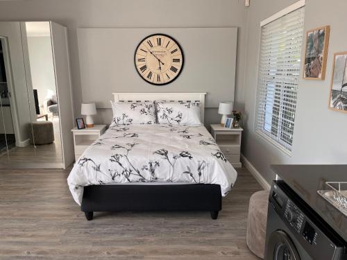 een slaapkamer met een bed met een klok aan de muur bij Cozy Cottage in Kaapstad