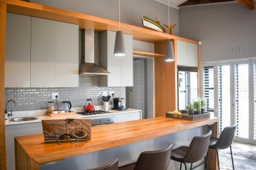 a kitchen with white cabinets and a wooden counter top at MOS-Palmiet 72 in Kleinmond