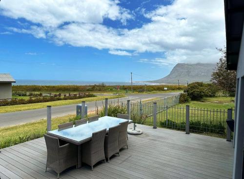 a table and chairs on a deck with a view of a road at MOS-Palmiet 72 in Kleinmond