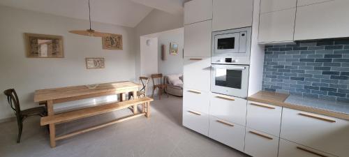 une cuisine avec des armoires blanches et une table en bois dans l'établissement Superbe Maison à la Remigeasse, proximité plage, à Dolus-d'Oléron