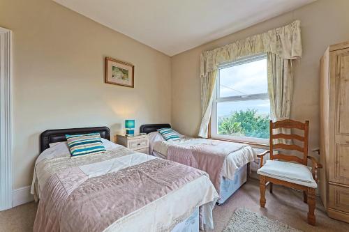 a bedroom with two beds and a chair and a window at Sunny Bank Guest House in Hythe