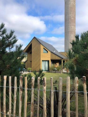 une maison derrière une clôture en bois avec un silo dans l'établissement La Maison Mimosa - Espace, Confort et Proche Plage, à Portbail