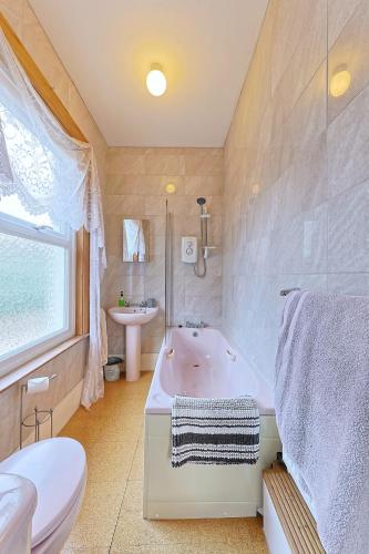a bathroom with a tub and a toilet and a sink at Sunny Bank Guest House in Hythe