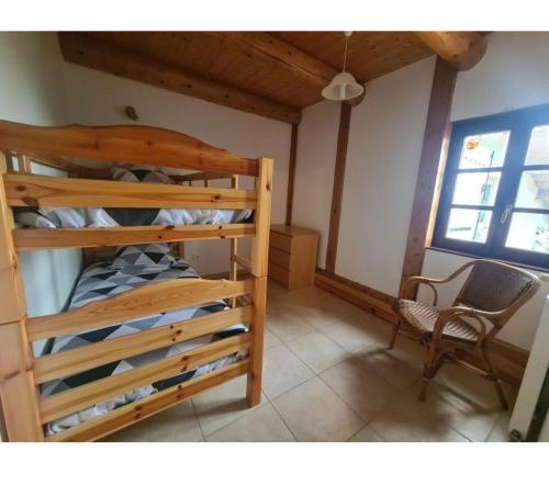 Un dormitorio con dos literas y una silla. en Gîte Les Bises, en Bronac
