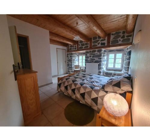 Un dormitorio con una cama y una pared de piedra. en Gîte Les Bises, en Bronac