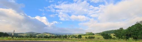un ciel nuageux avec un champ et une route dans l'établissement Gîte Les Bises, à Bronac