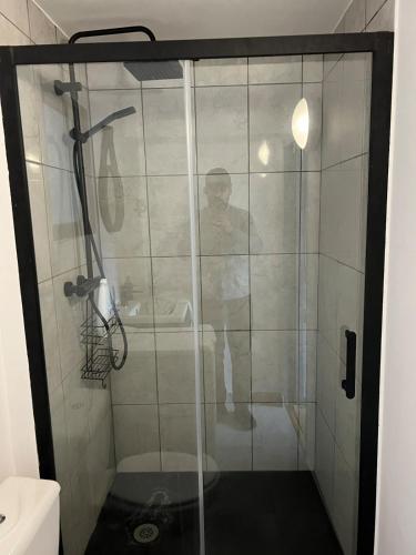 un homme debout dans une douche dans la salle de bains dans l'établissement Appartement proche Champs Élysée Paris 8e, à Paris