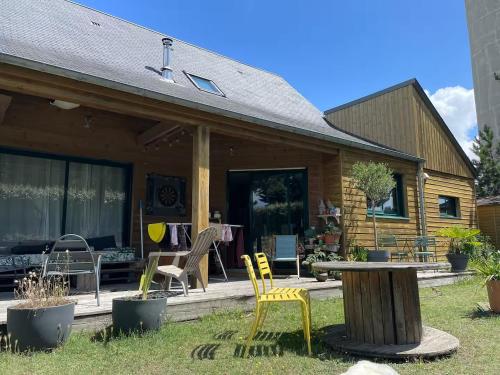 a house with chairs and a table in the yard at La Maison Mimosa - Espace, Confort et Proche Plage in Portbail