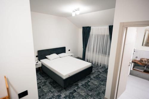 a white bedroom with a bed and a window at Vila Tudor in Borşa