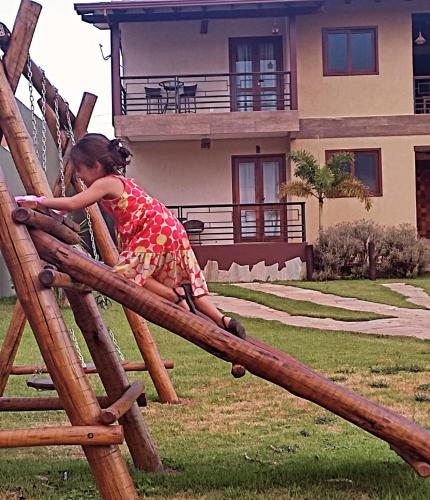 a little girl is climbing on a wooden slide at Apartamento no centro, parceria no vale da Lua, Cachoeira dos Cristais e academia - reserve agora! in Alto Paraíso de Goiás