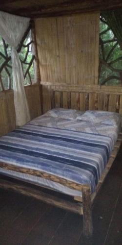 a large wooden bed in a wooden room at Cabanas Armonia in Cotundo