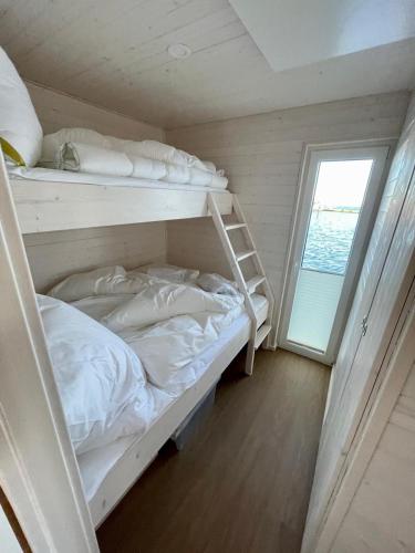 a bedroom with two bunk beds and a window at Hausboot Lillemor Burgtiefe in Fehmarn