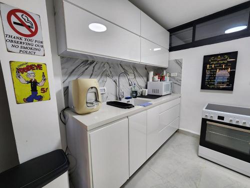 a kitchen with white cabinets and a sign on the wall at דופלקס כנרת in Tiberias