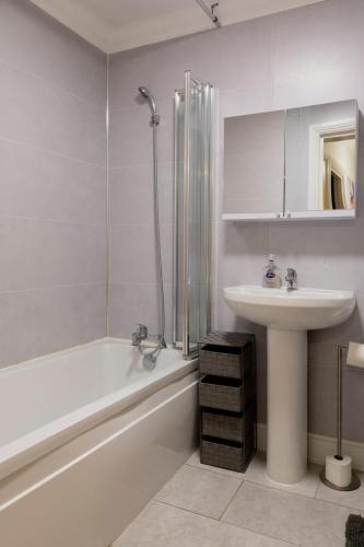 a bathroom with a sink and a tub and a toilet and a sink at Ocean waves apartment near Bournemouth beach in Bournemouth