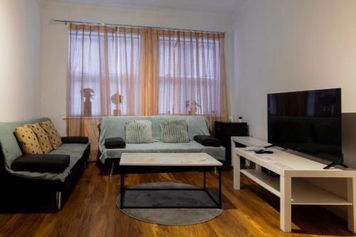a living room with a couch and a tv at Ocean waves apartment near Bournemouth beach in Bournemouth