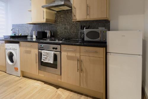 a kitchen with a refrigerator and a washer and dryer at Ocean waves apartment near Bournemouth beach in Bournemouth