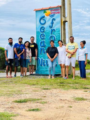 a group of people standing in front of a sign at Ocean Front Villa in Hikkaduwa
