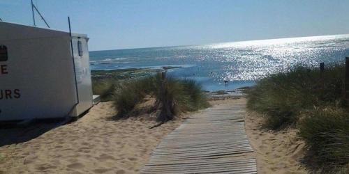 a wooden path leading to a beach with the ocean at Superbe Logement à 200 m de la Plage ! T4 Coquillages in Saint-Pierre-dʼOléron