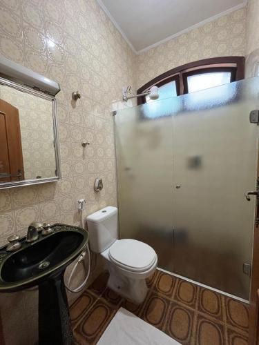 a bathroom with a shower and a toilet and a sink at Vila Mar Suítes in Bertioga