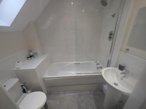 a bathroom with a tub and a toilet and a sink at Stunning Modern 2 Bedroom Apartment - Perfect Getaway in Manchester