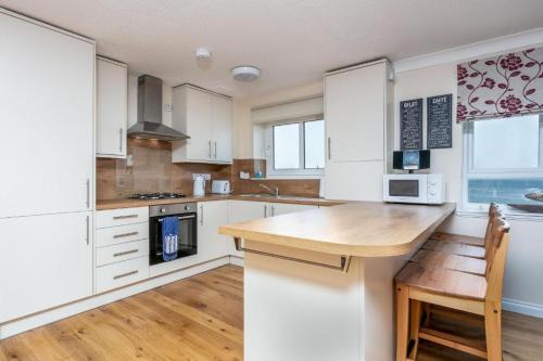 a kitchen with white cabinets and a wooden counter top at Arran View - Coorie Doon Stays in Ayr