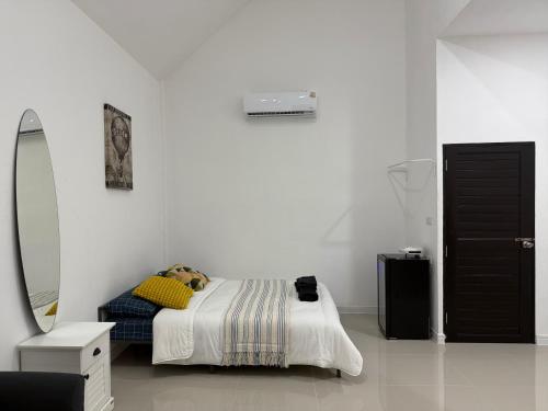 a white bedroom with a bed and a mirror at PMEs Home in Ban Wang Kanhuat