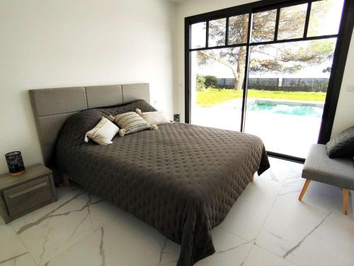 une chambre avec un lit et une grande fenêtre dans l'établissement Villa 12 pers avec piscine chauffée et vue exceptionnelle, première ligne Bassin d'Arcachon - FR-1-736-32, à Lège-Cap-Ferret