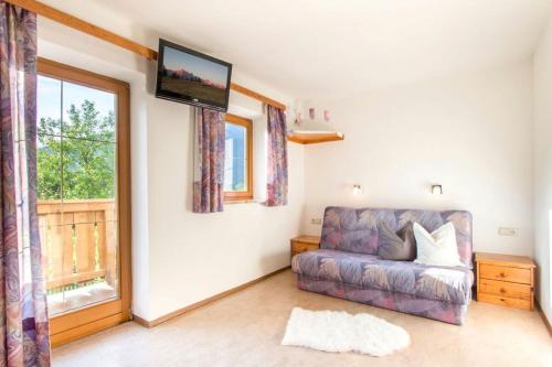 a living room with a couch and a tv on the wall at Ferienwohnung Haus Waldheim in Werfenweng