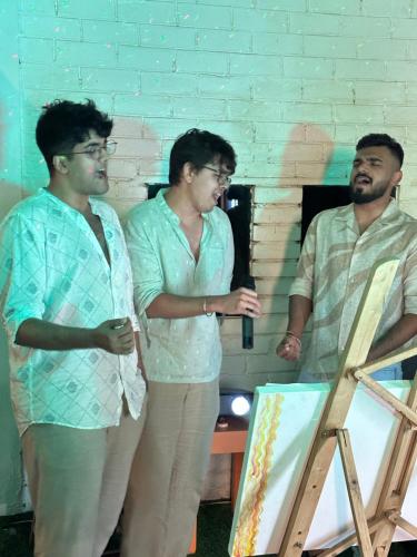 a group of three men standing next to a painting at Summer Hostel in Palolem