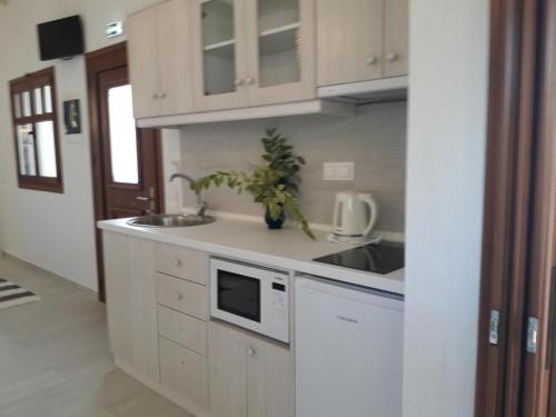 a white kitchen with a sink and a microwave at Maistros Holiday Home in Vourvourou