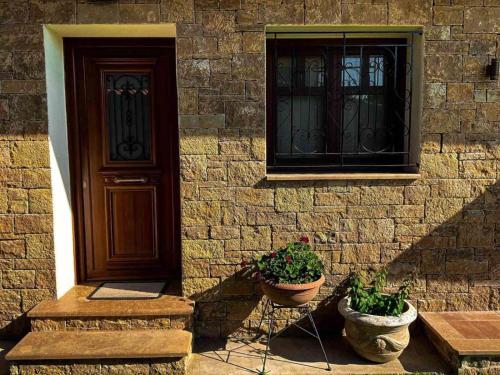 a building with two potted plants in front of a door at Maistros Holiday Home in Vourvourou