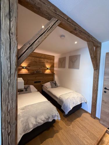 two beds in a room with wooden walls at Alpine Lodge Brixen in Brixen im Thale