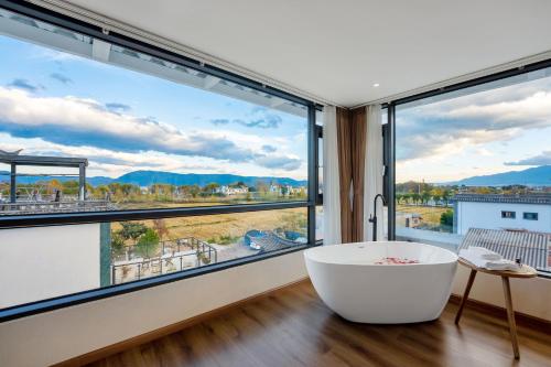 a large white bath tub in a room with large windows at Xizhou Feng Shangju in Dali
