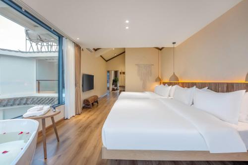 a large white bed in a room with a tub at Xizhou Feng Shangju in Dali