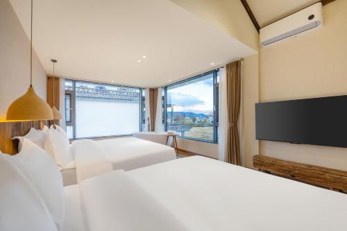 a bedroom with two white beds and a flat screen tv at Xizhou Feng Shangju in Dali