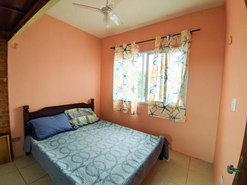 a bedroom with a bed and a window at Casa de Praia Aconchegante in Peruíbe
