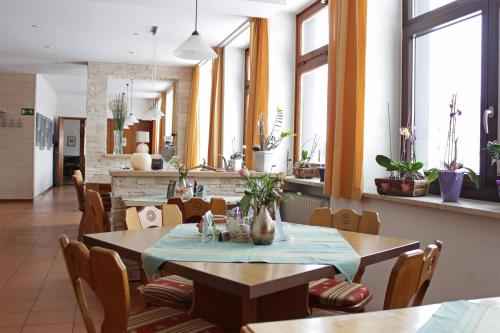 ein Restaurant mit Holztischen, Stühlen und Fenstern in der Unterkunft Berggasthof Lusen in Neuschönau