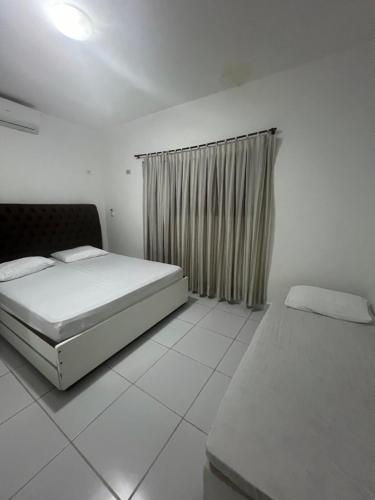 ein weißes Schlafzimmer mit zwei Betten und einem Fenster in der Unterkunft Casa Itamaracá in Itamaracá