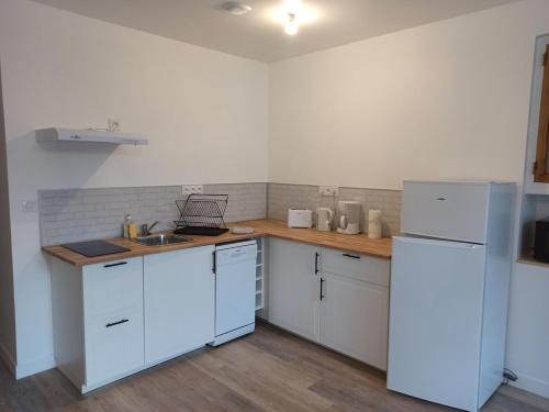 une cuisine avec des armoires blanches et un réfrigérateur blanc dans l'établissement Appartement 2 à 4 personnes proche de la mer, à Saint-Jean-le-Thomas
