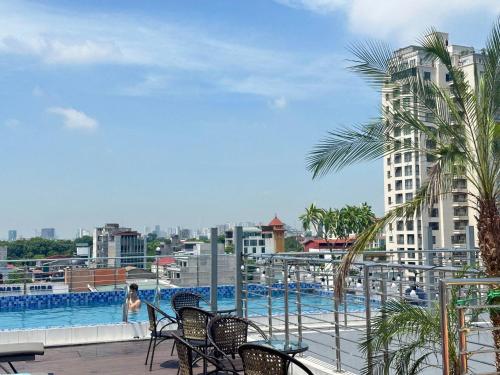 a woman standing on a balcony with a swimming pool at Luxe Paradise Premium Hotel and Spa in Hanoi