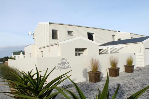 a white house with plants in front of it at Spatalla Holiday Homes in Kleinmond
