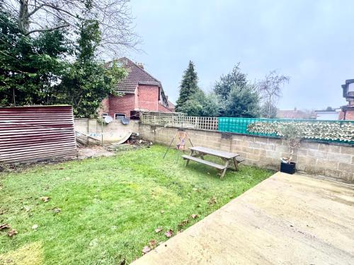 a backyard with a wooden bench in the grass at Recently fully refurbished --January 2026-- private en-suite room with brand-new bathroom and private entrance in Oxford