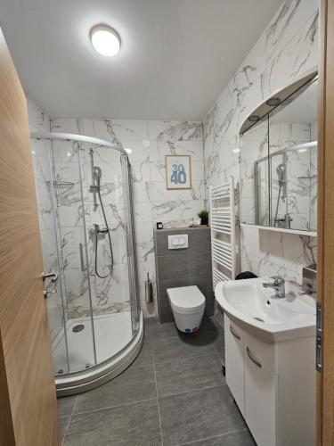 a bathroom with a shower and a toilet and a sink at OnPoint Apartmani in Osijek