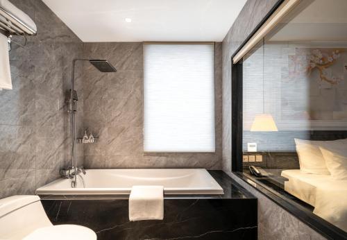 a bathroom with a bath tub and a bed at Luxe Paradise Premium Hotel and Spa in Hanoi