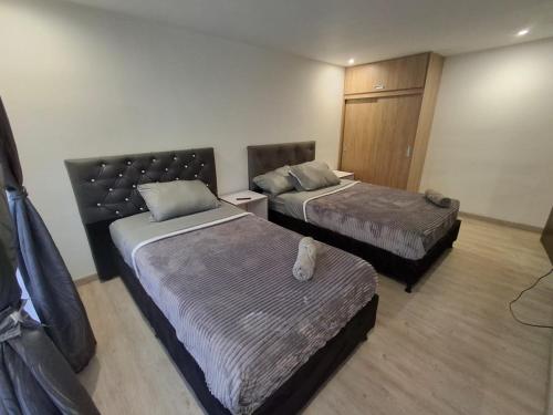 a hotel room with two beds and a bench in it at Hermosa casa con espacios independientes cerca a Mall plaza in Manizales