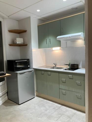 - une cuisine avec des placards verts, un évier et une cuisinière dans l'établissement Lovely Mulhouse Apartment, à Mulhouse