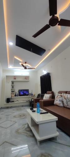 a living room with a couch and a ceiling fan at Aneesha's Residence in Surūrnagar