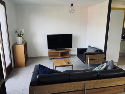a living room with a couch and a flat screen tv at Villa avec vue lac panoramique proche de la plage in Conjux