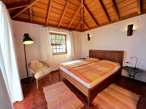 une chambre avec un grand lit et une chaise dans l'établissement Casa Barbara, à Puntagorda